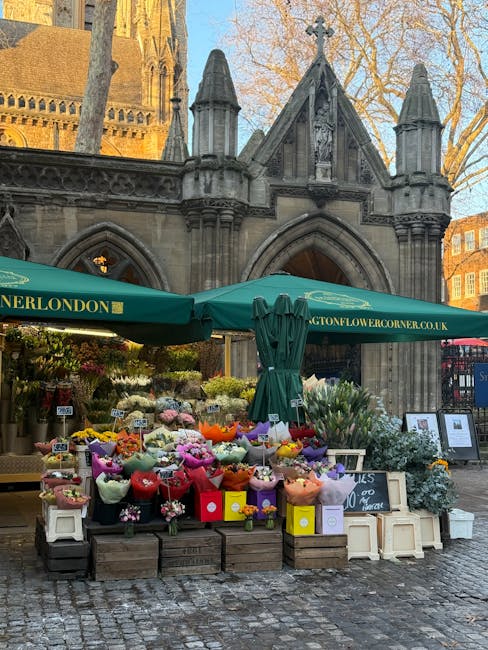 A vibrant outdoor flower stall situated in front of a historic stone church with Gothic architectural features, including pointed arches and decorative pinnacles, during daylight hours. The stall, und